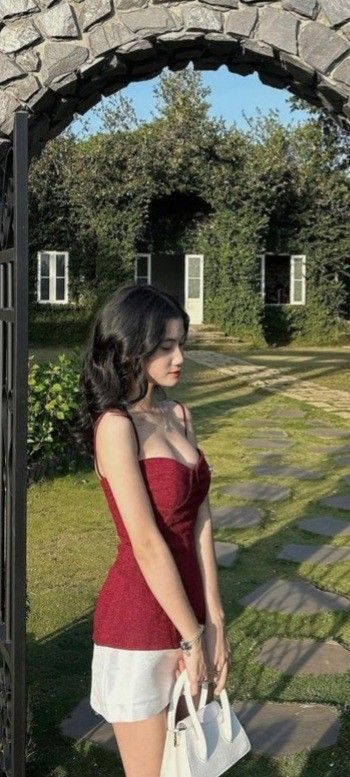 Cô gái xinh đẹp trong áo hai dây đỏ và váy trắng bên vườn xanh