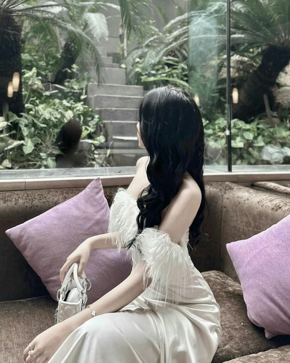 Cô gái xinh đẹp trong chiếc đầm trắng ngồi trên ghế sofa