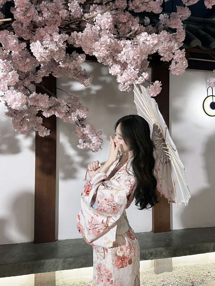 Cô gái xinh đẹp trong kimono trắng giữa hoa anh đào rực rỡ