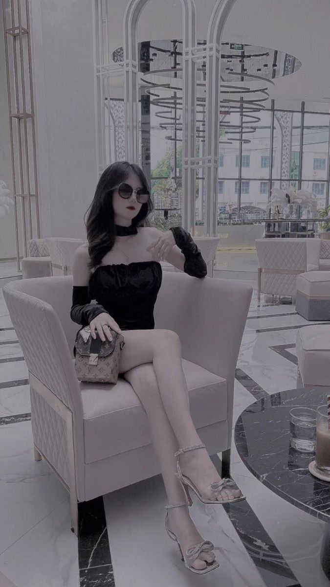 Cô gái xinh đẹp trong trang phục đen ngồi trên sofa sang trọng