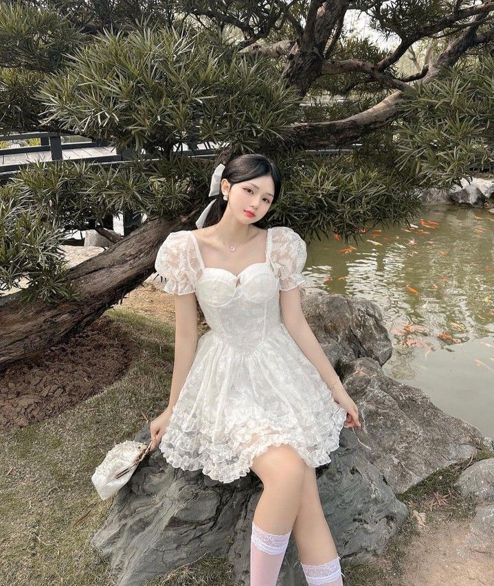 Cô gái xinh đẹp trong trang phục trắng bên hồ nước