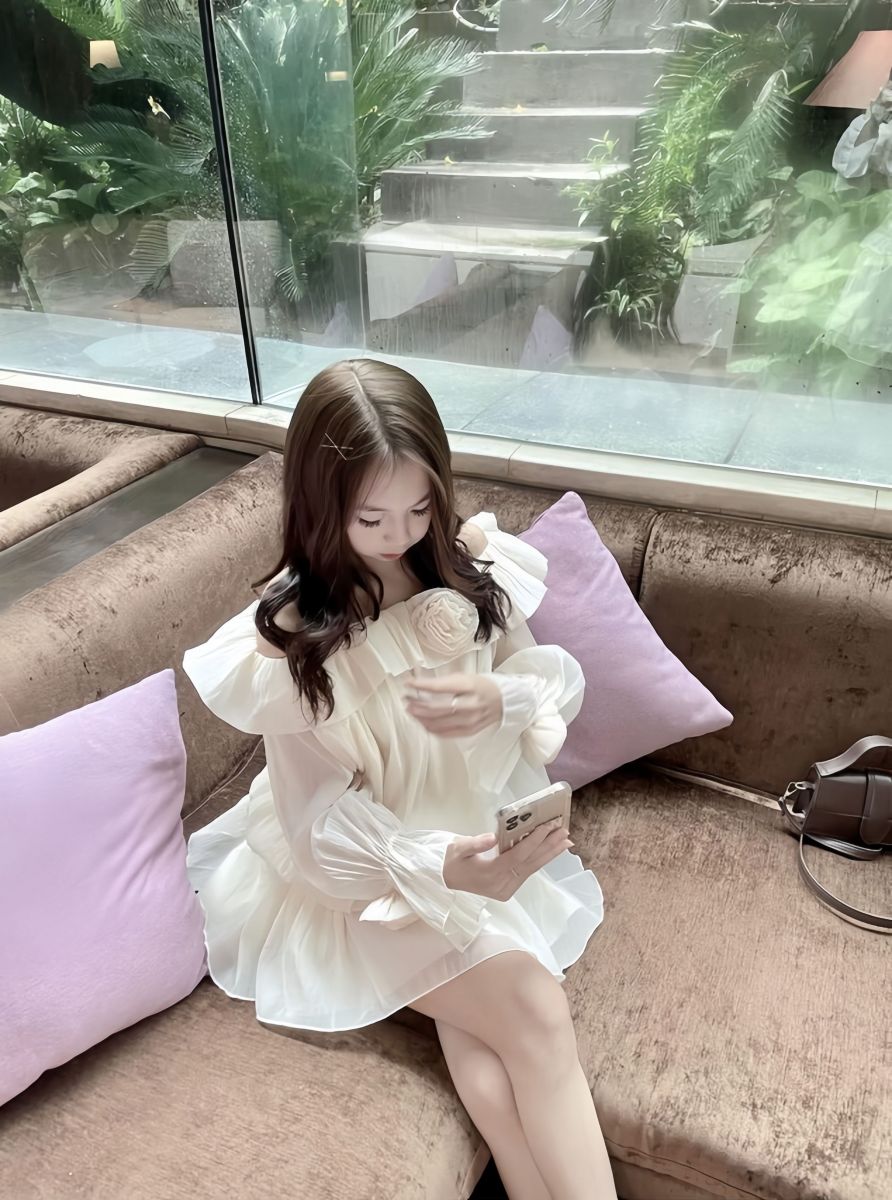 Cô gái xinh đẹp trong váy trắng ngồi trên sofa