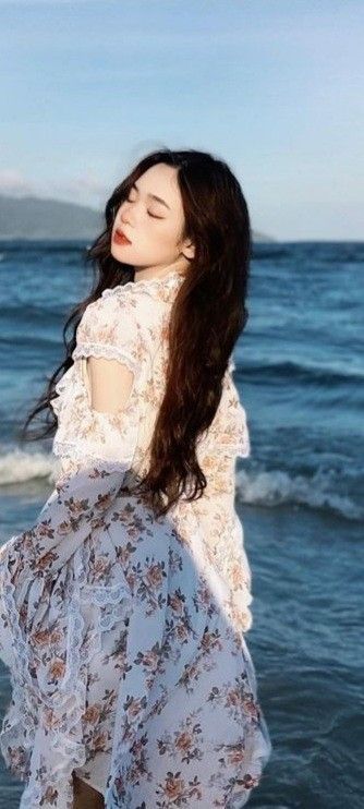 Cô gái xinh đẹp trong váy trắng nhìn ra biển