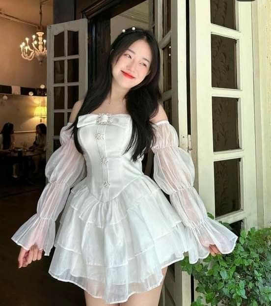 Cô gái xinh đẹp trong váy trắng tại quán cà phê