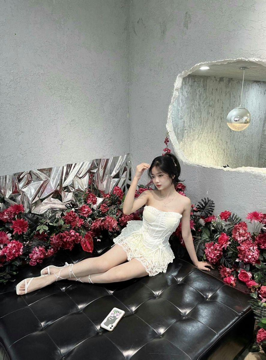 Cô gái xinh đẹp trong váy trắng trên ghế sofa đen