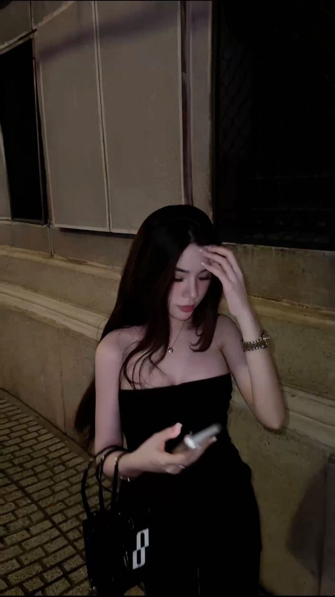 Cô gái xinh đẹp với áo hai dây đen trên vỉa hè