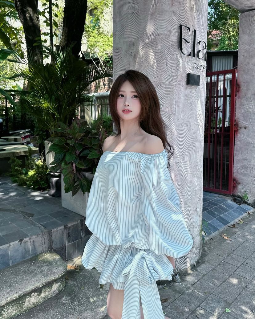 Cô gái xinh mặc áo off-shoulder bên tường quán cafe