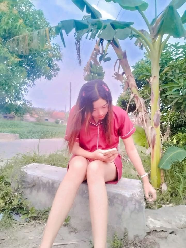 Cô gái xinh mặc đồ ngủ ngồi bên bờ đá trong khung cảnh thiên nhiên