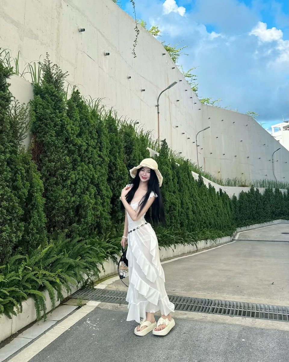 Cô gái xinh mặc váy trắng bên cây xanh