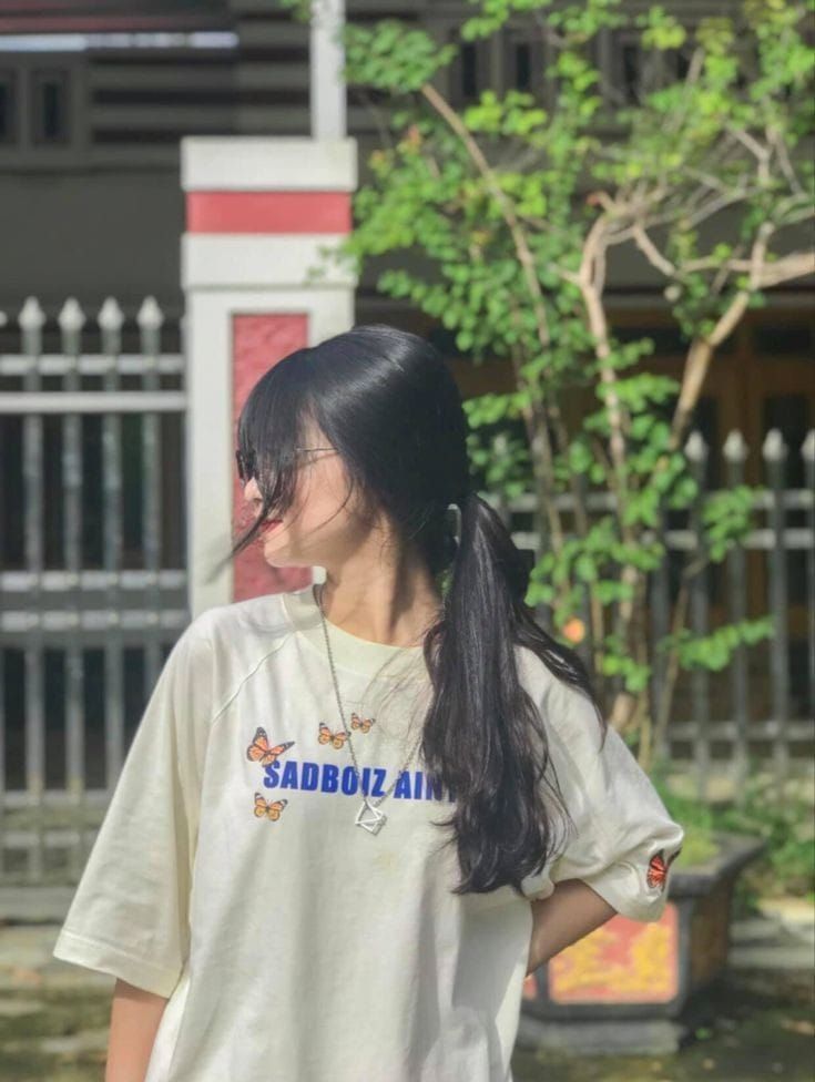 Gái đeo kính với áo thun sáng màu bên cây xanh
