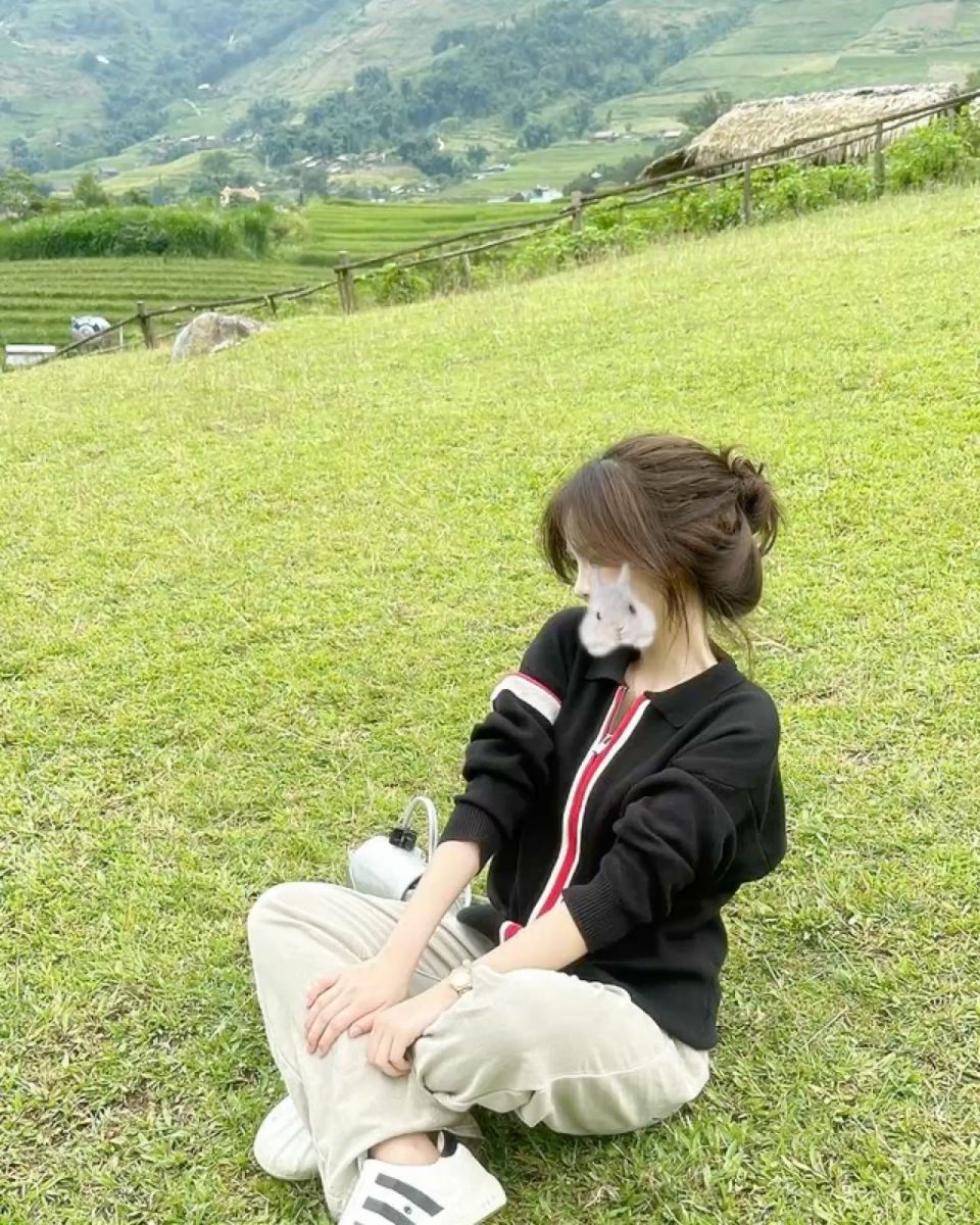 Gái đẹp mặc áo khoác đen nổi bật bên cây xanh