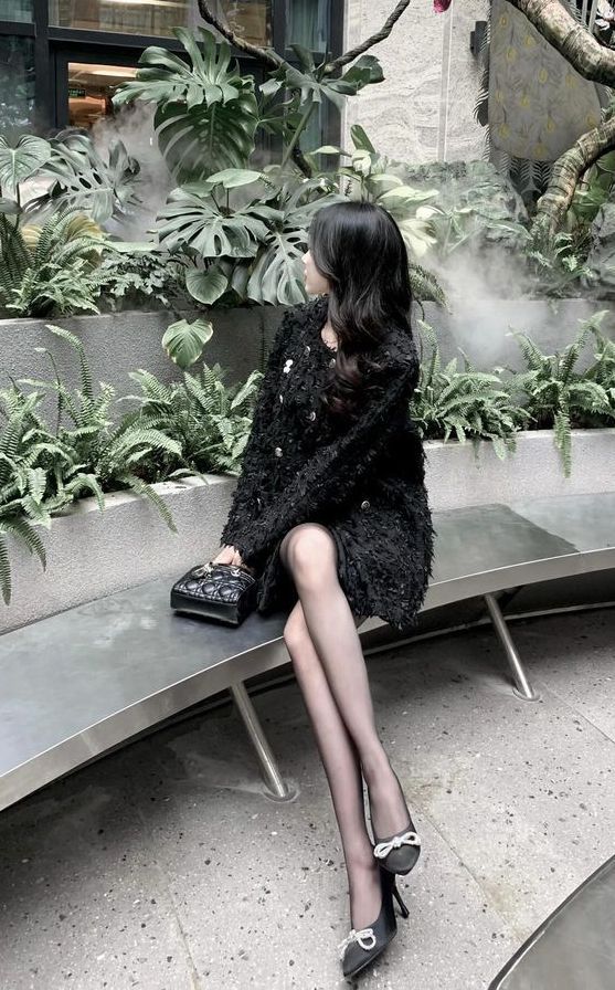 Gái đẹp mặc áo khoác lông đen và chân váy ngắn trong khu vườn