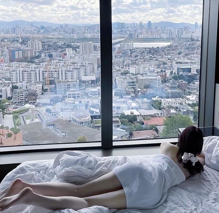 Gái đẹp mặc áo tắm ngắm nhìn thành phố qua cửa sổ lớn