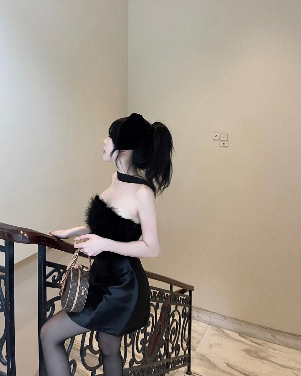 Gái đẹp mặc váy đen chi tiết lông đứng bên lan can cầu thang
