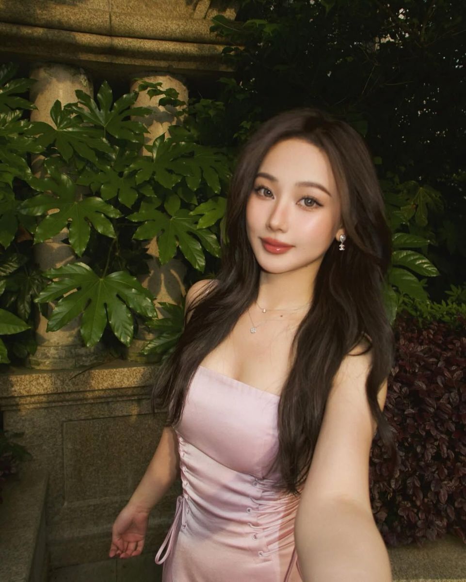 Gái đẹp mặc váy hồng chụp hình selfie giữa tán cây xanh