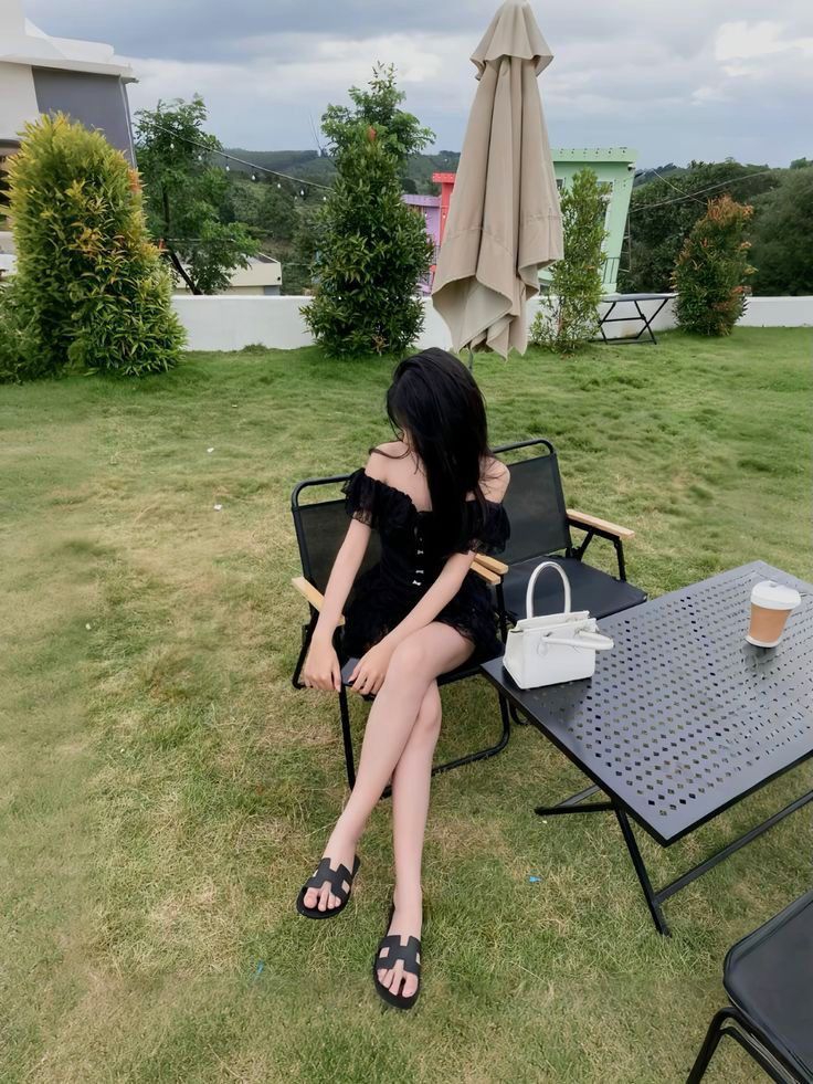 Gái đẹp mặc váy ngồi trên ghế tại quán cà phê ngoài trời