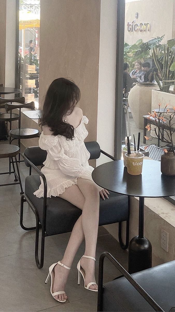 Gái đẹp mặc váy trắng ngồi thư giãn tại quán cà phê