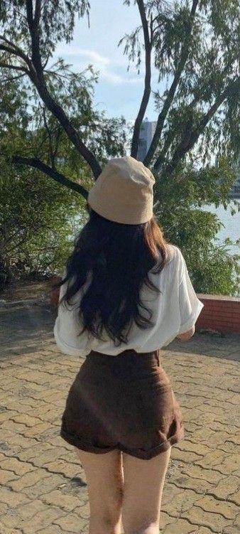 Gái đẹp trong áo trắng và quần short nâu tại công viên xanh mát