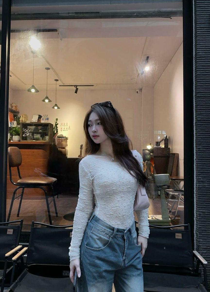 Gái mặc áo sơ mi trắng và quần jeans rộng tại quán cà phê