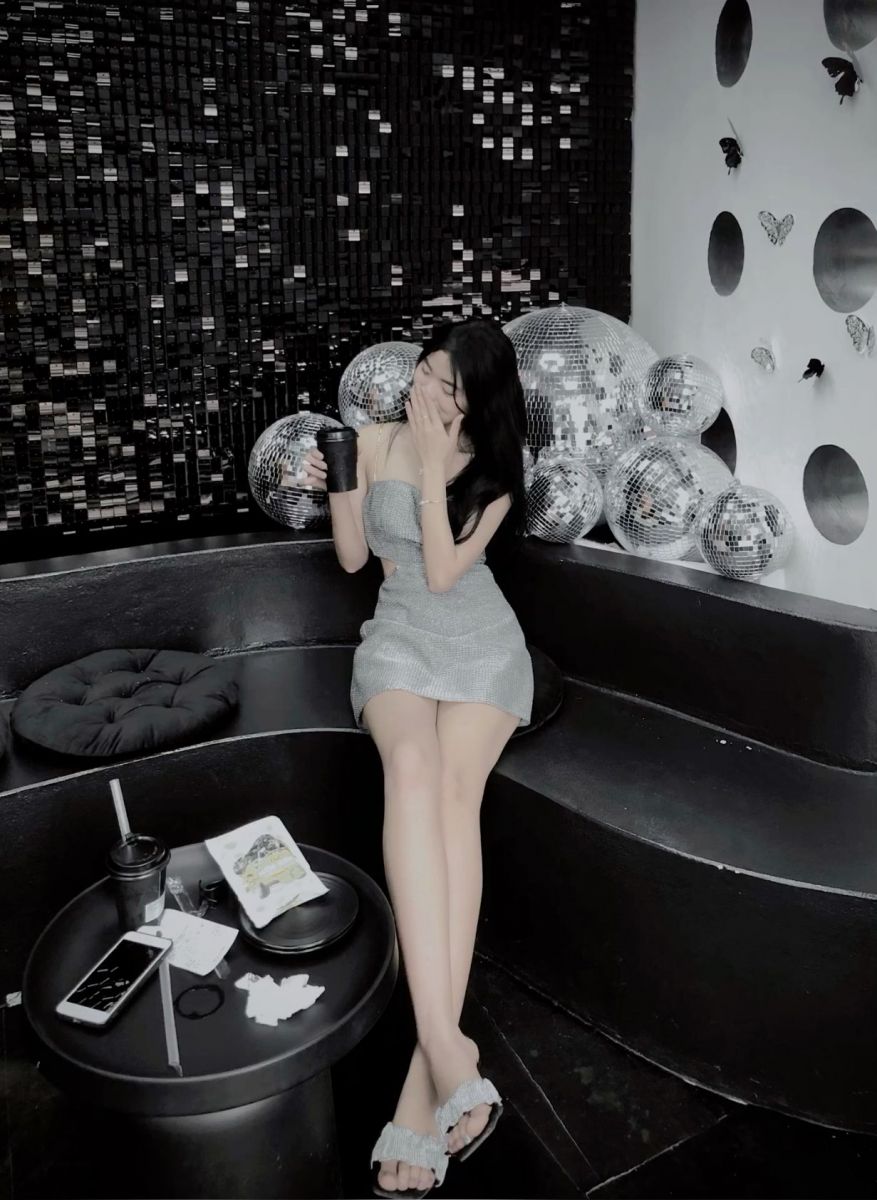Gái mặc váy ngắn ngồi trên ghế sofa trong quán bar tối