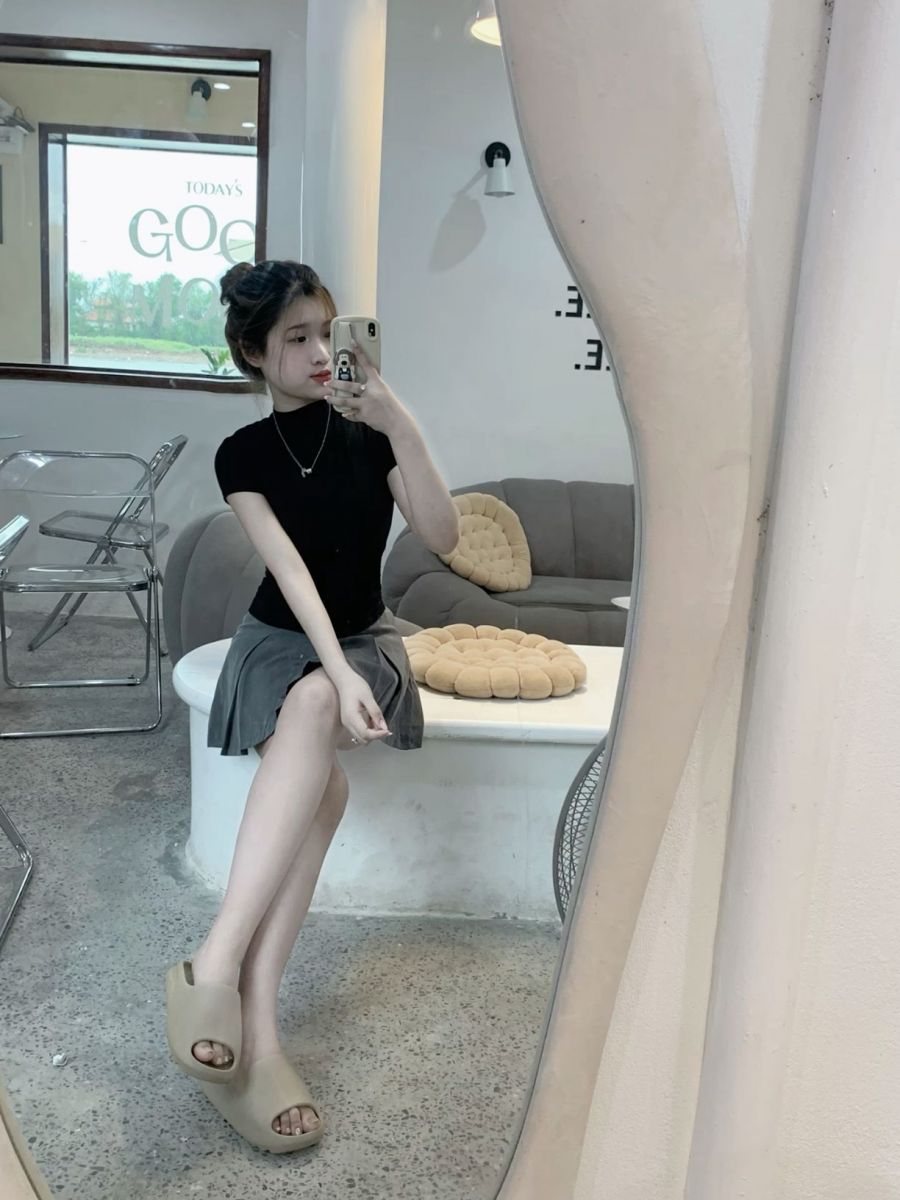 Gái trẻ mặc áo thun đen và chân váy xám chụp ảnh trong gương