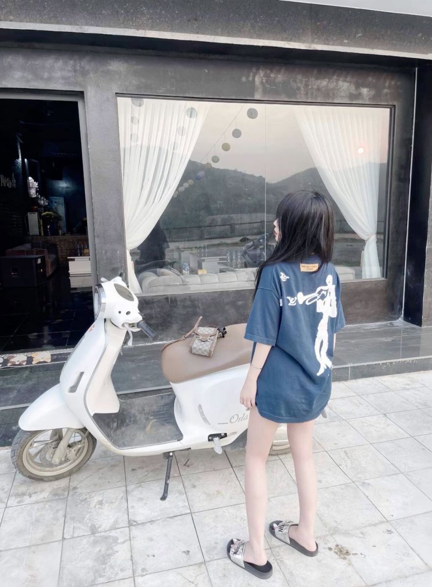 Gái trẻ mặc áo thun rộng bên xe máy trắng