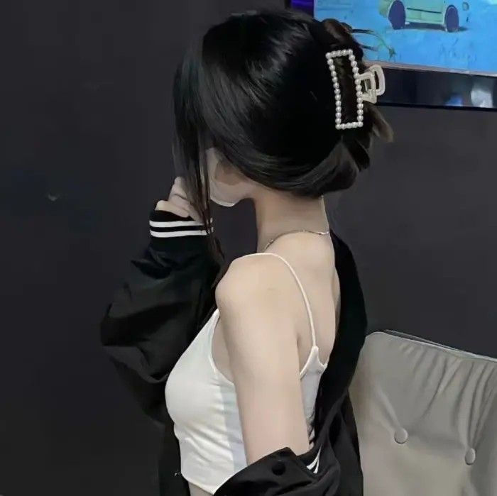 Gái trẻ mặc áo trắng mỏng và áo khoác đen nghiêng mình trong không gian tối giản