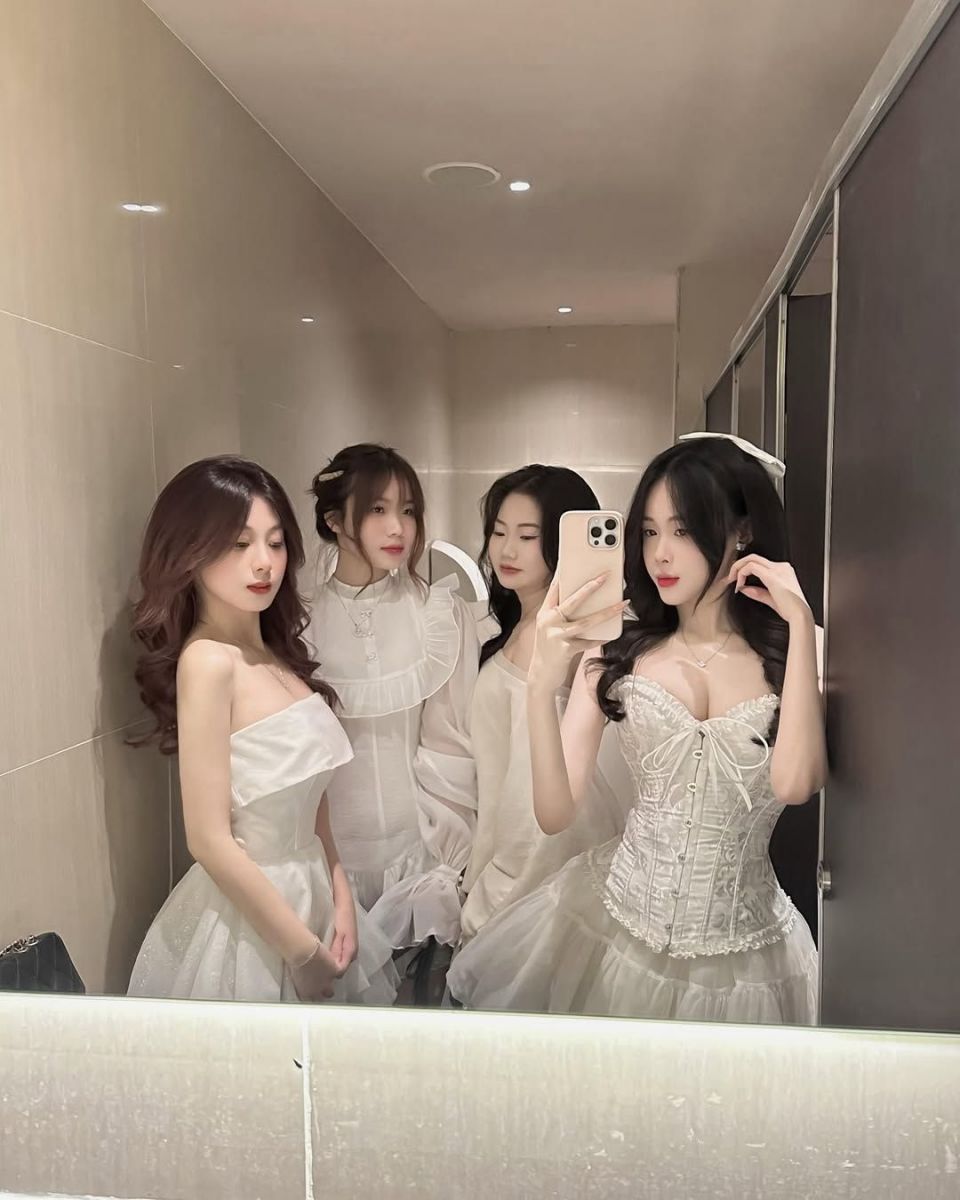 Gái trẻ trong trang phục trắng tạo dáng chụp ảnh bên gương
