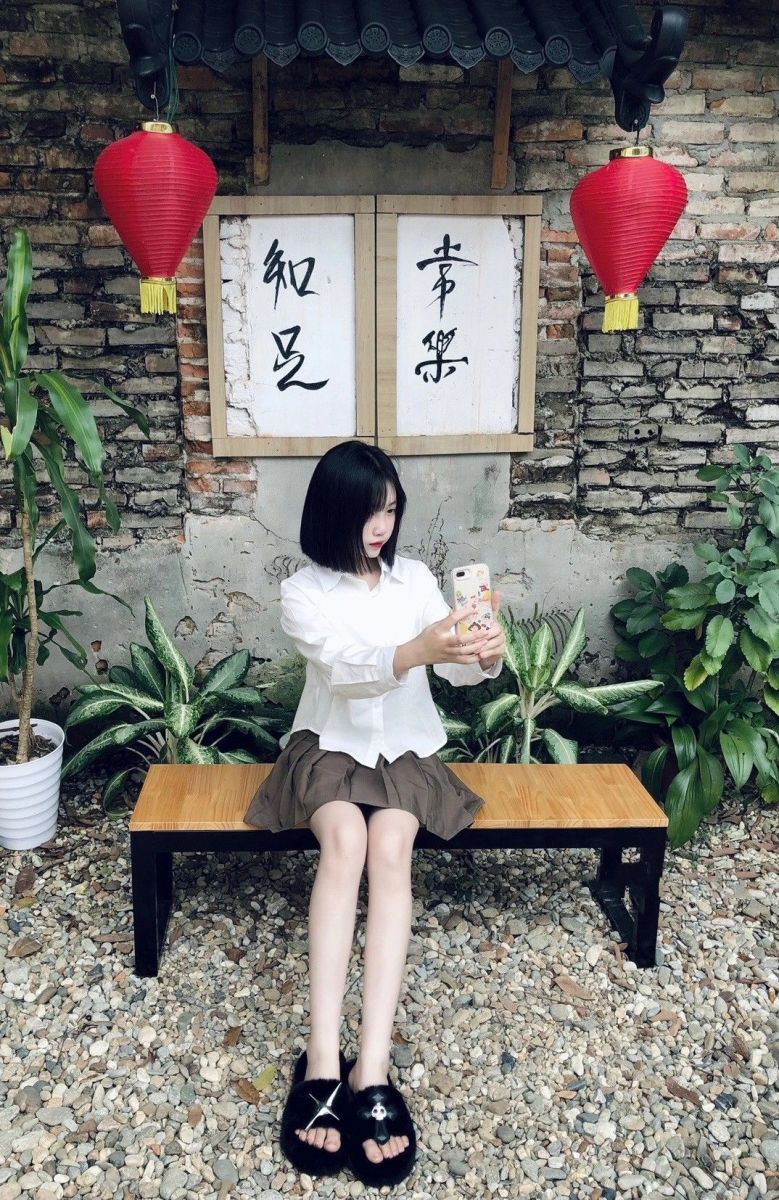 Gái trẻ xinh đẹp trong bộ đồ blouse trắng và chân váy nâu