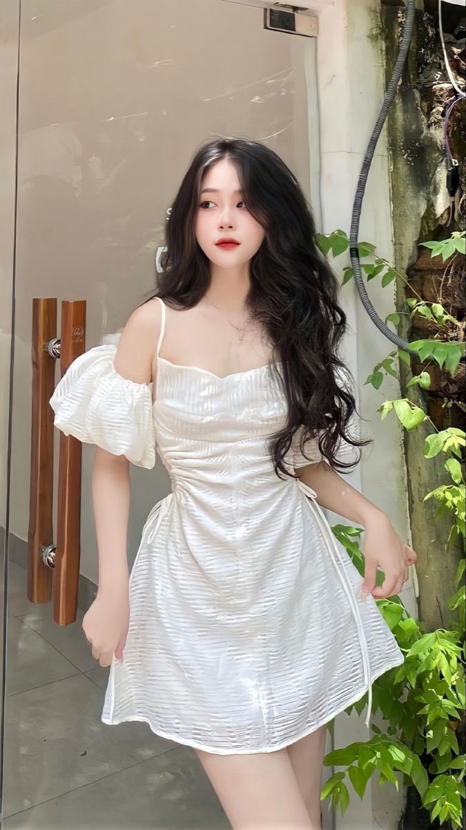 Gái trẻ xinh đẹp trong chiếc đầm trắng trước cổng nhà