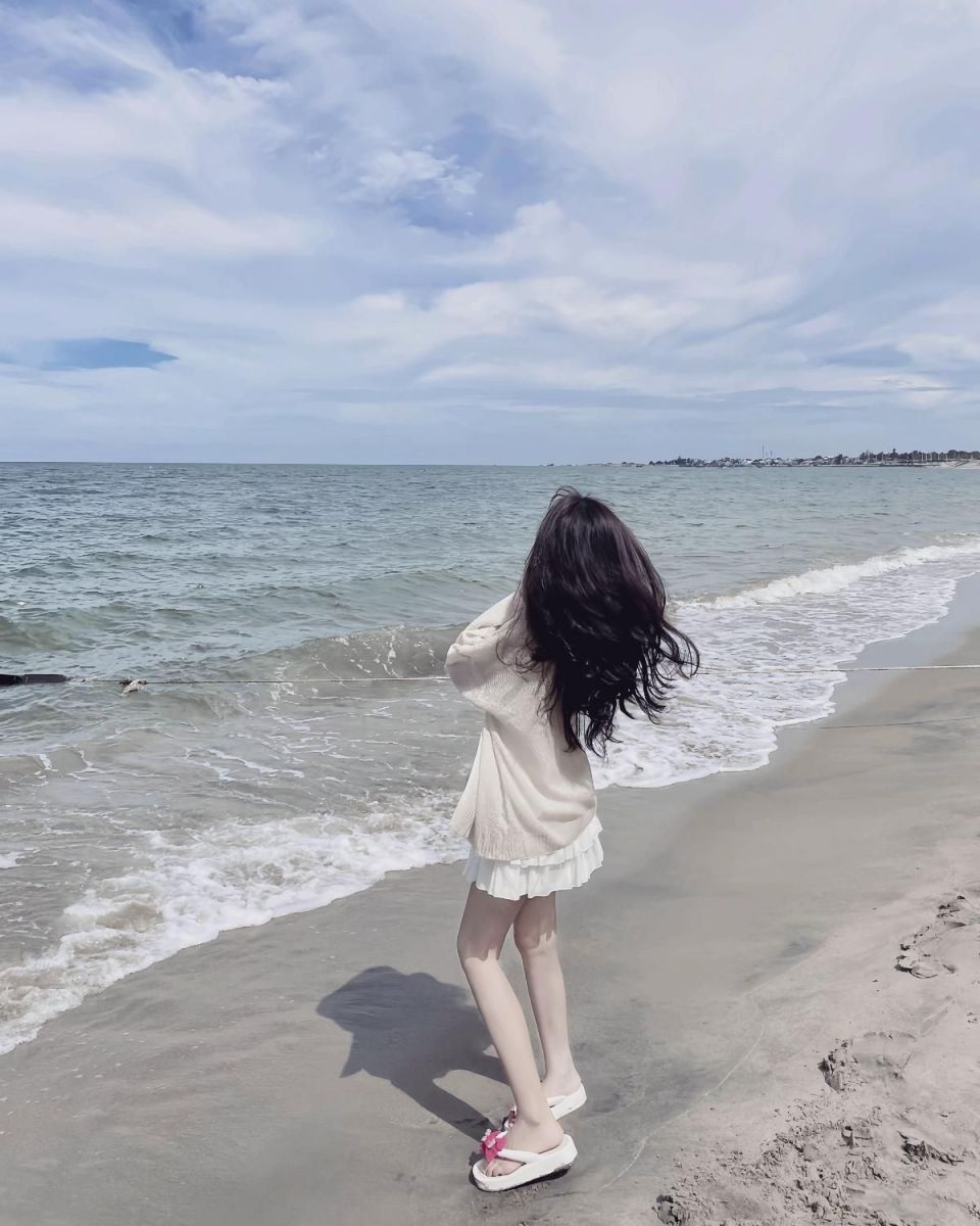 Gái xinh chân dài mặc cardigan trắng bên bờ biển