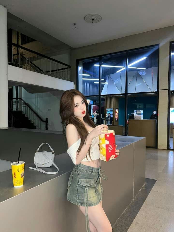 Gái xinh diện áo crop top trắng và chân váy denim tại trung tâm thương mại