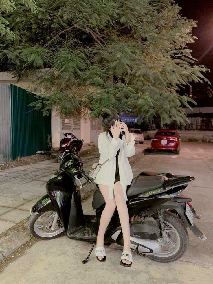 Gái xinh diện áo khoác trắng bên xe máy đêm khuya
