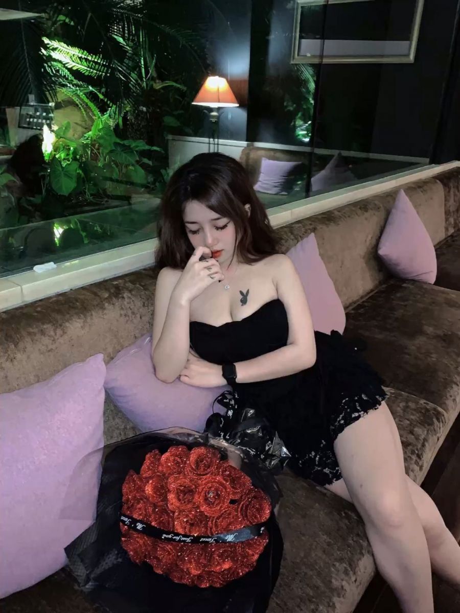 Gái xinh diện đầm đen ngồi trên ghế sofa cam