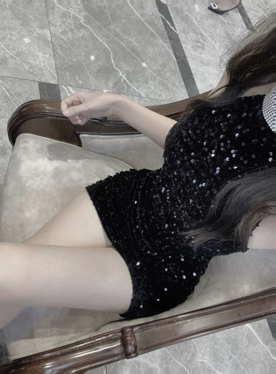 Gái xinh diện đầm đen sequin tạo dáng trên ghế sofa sang trọng