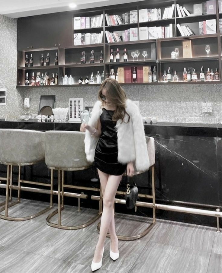 Gái xinh diện đầm đen và áo khoác long trắng tại bar sang trọng