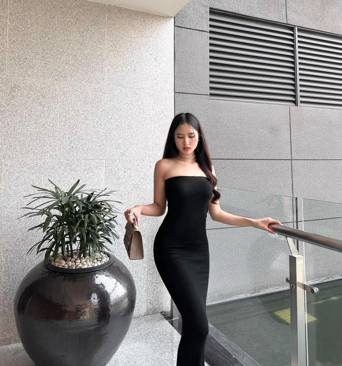 Gái xinh diện váy đen bên cây xanh trong không gian hiện đại