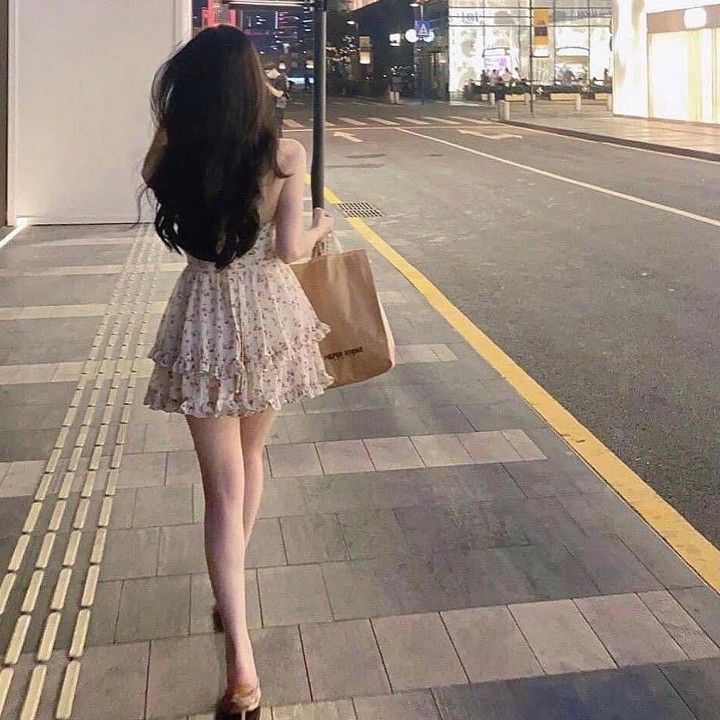 Gái xinh diện váy ngắn, cầm túi xách đi bộ trên phố