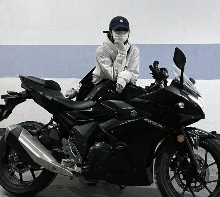 Gái xinh không mặc áo với hoodie trắng và mũ lưỡi trai trên xe moto đen