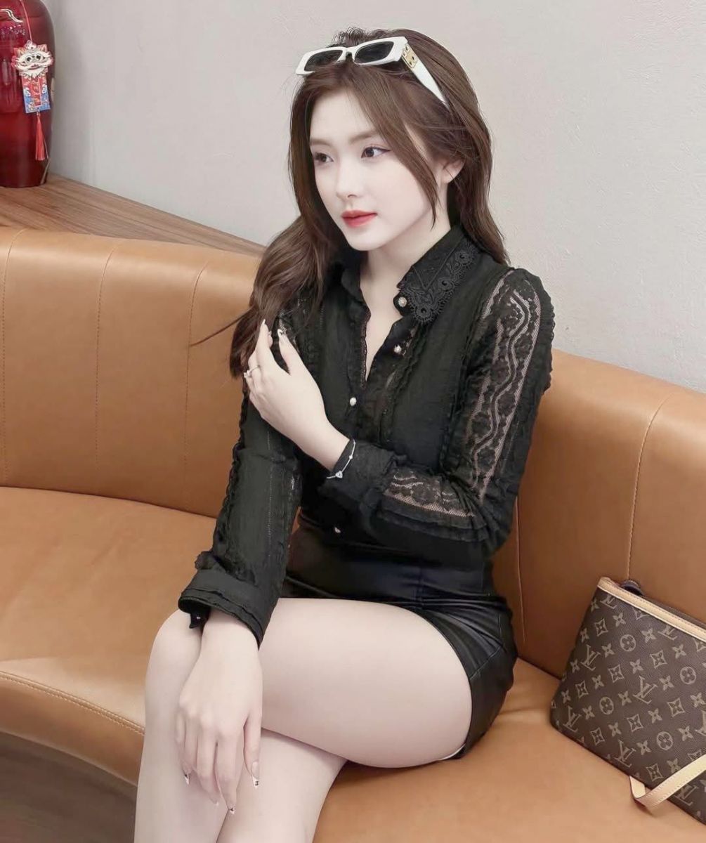 Gái xinh mặc áo blouse đen và chân váy đa sắc trên ghế sofa