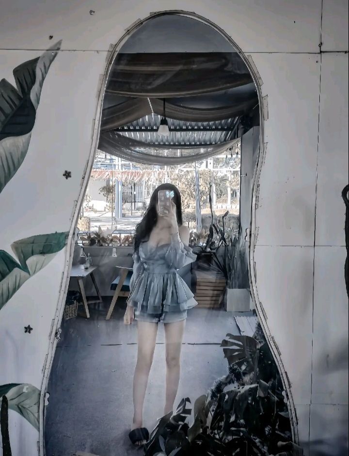 Gái xinh mặc áo blouse xanh và quần shorts ngắn tại quán cà phê
