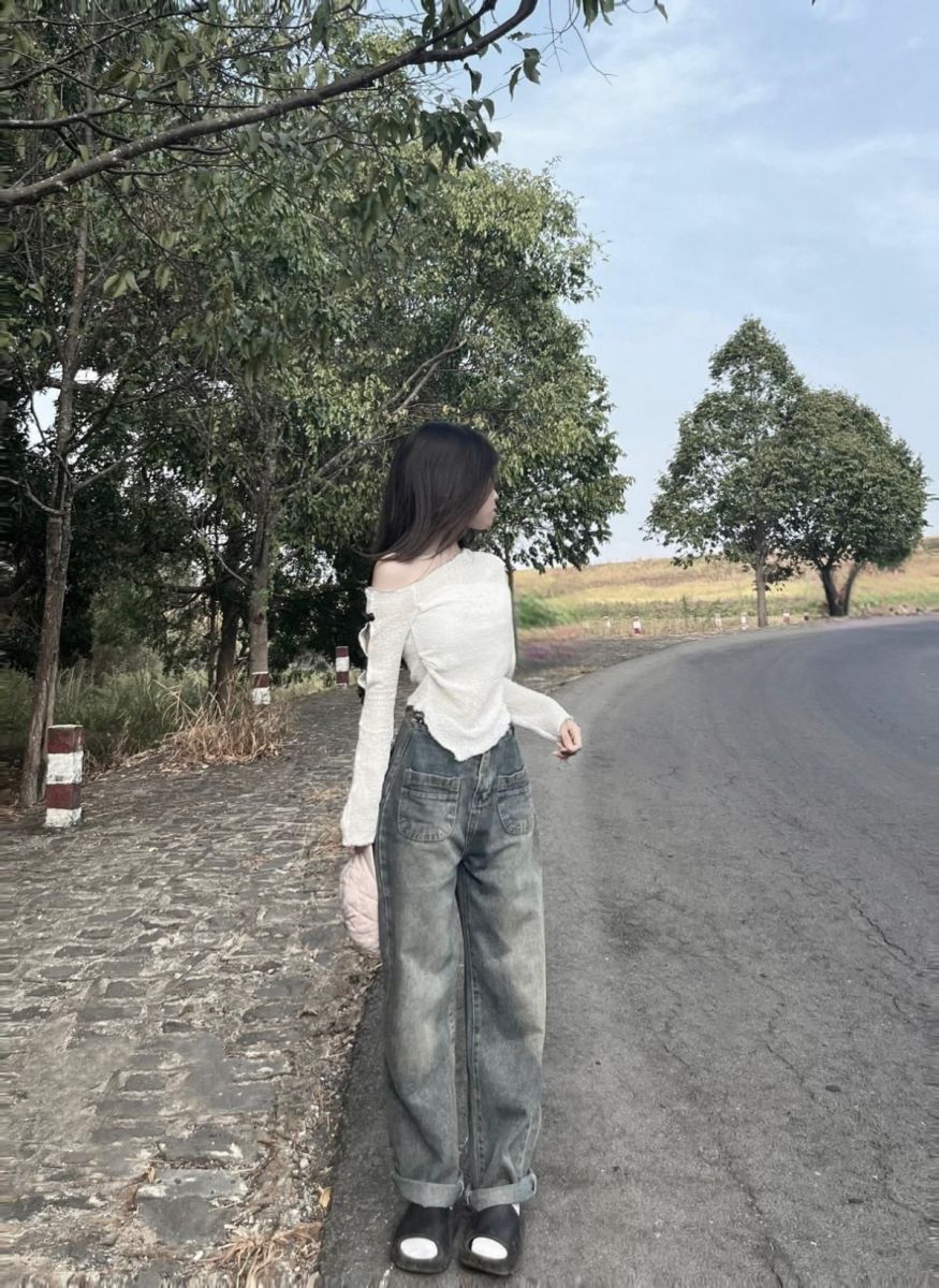 Gái xinh mặc áo cadigan trắng và quần jeans rộng bên cây xanh tươi