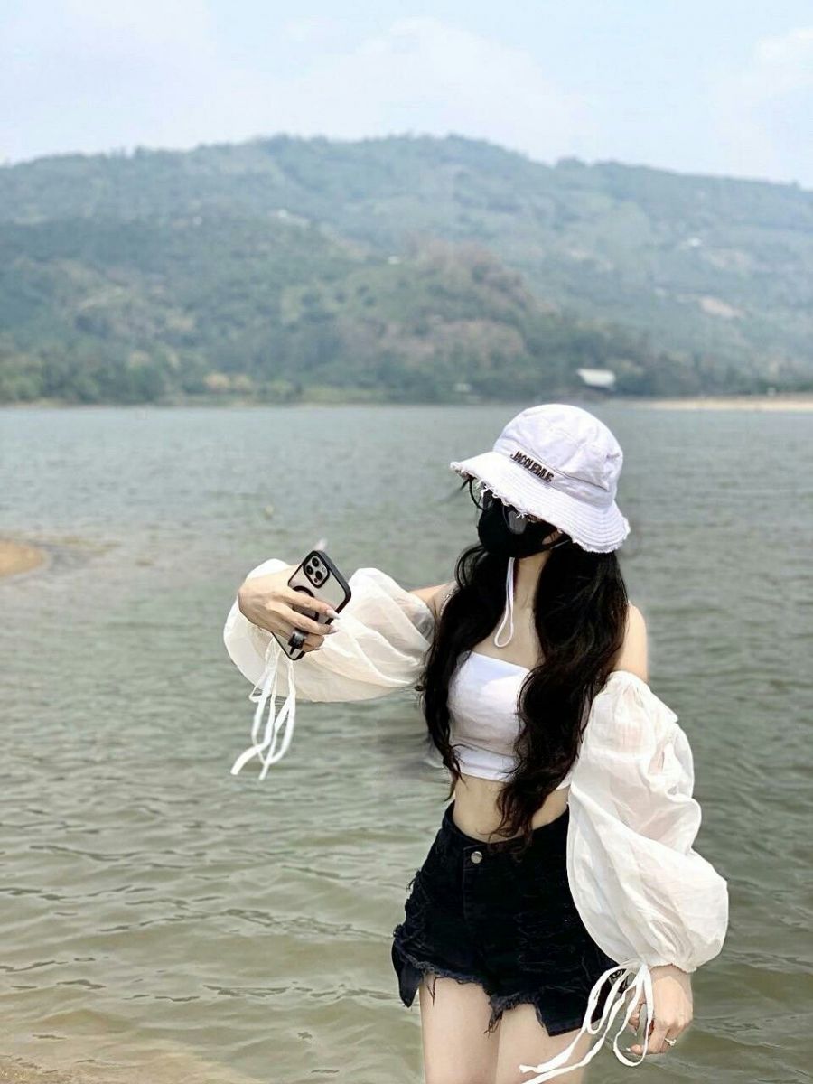 Gái xinh mặc áo crop top trắng và quần short đen giữa hồ nước
