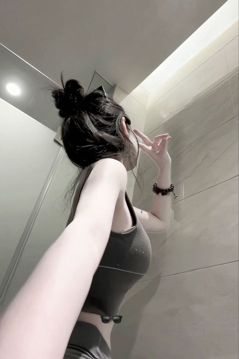 Gái xinh mặc áo crop top xám và quần ôm tạo dáng selfie