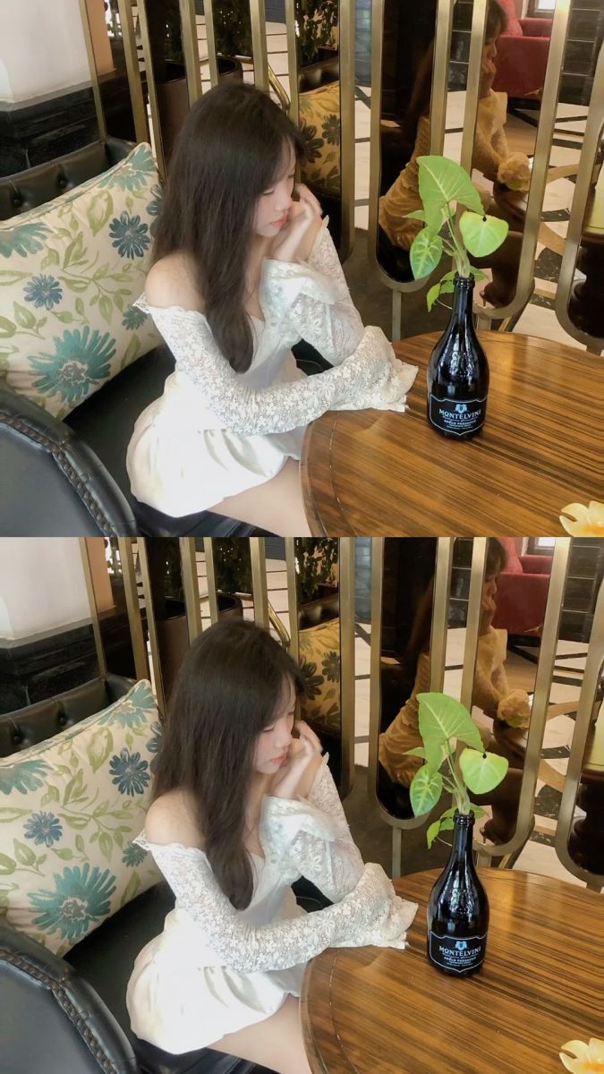 Gái xinh mặc áo dài trắng bên bàn gỗ trong quán cà phê sang trọng