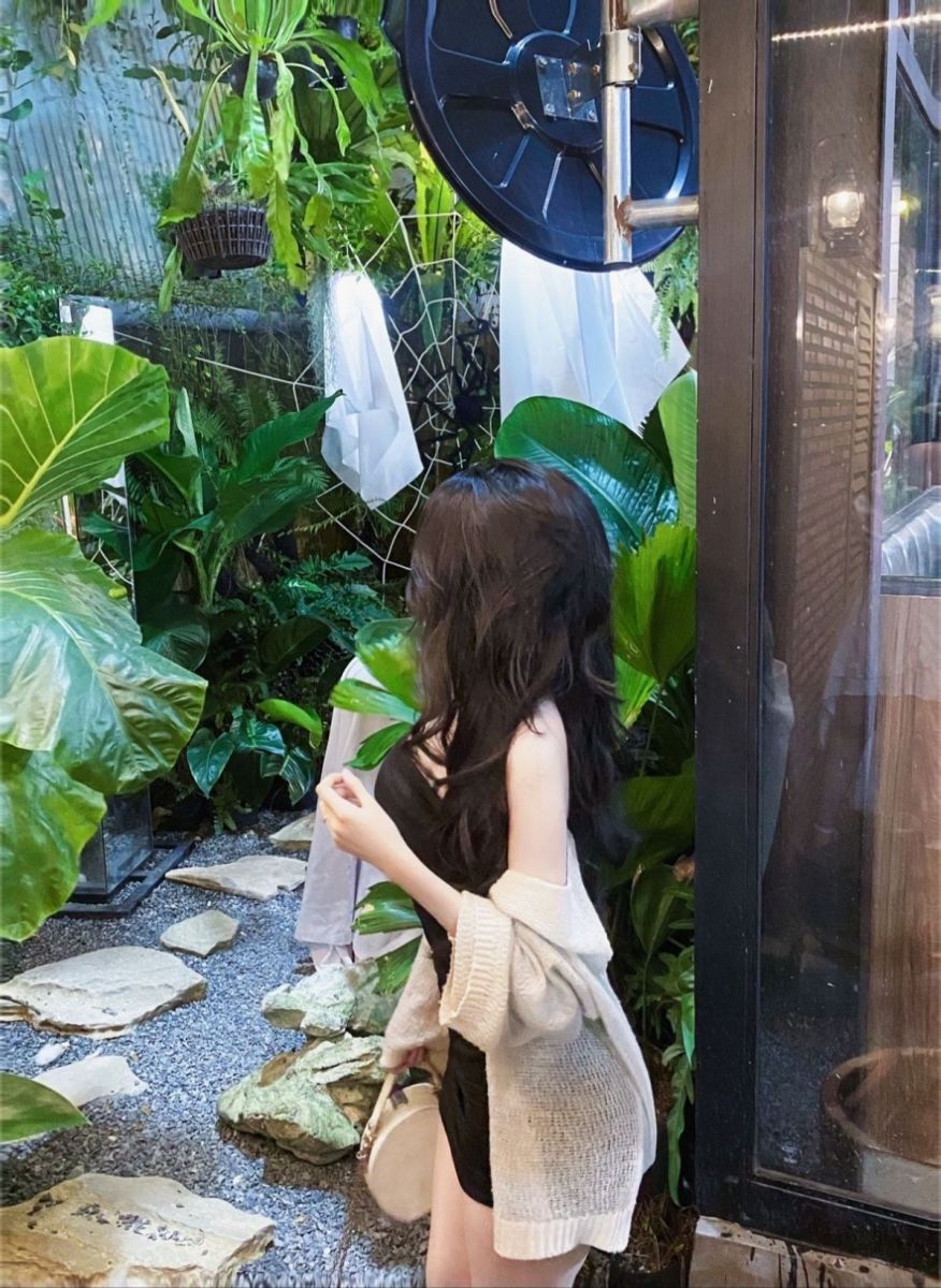 Gái xinh mặc áo đầm đen và cardigan màu sáng giữa khu vườn xanh mát