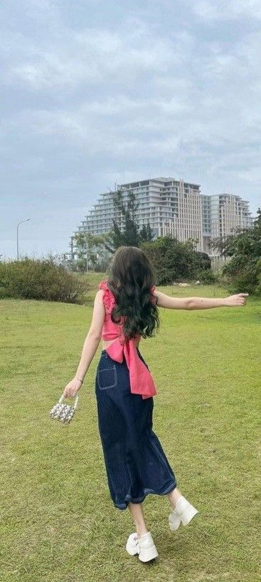 Gái xinh mặc áo hồng và chân váy denim tại công viên