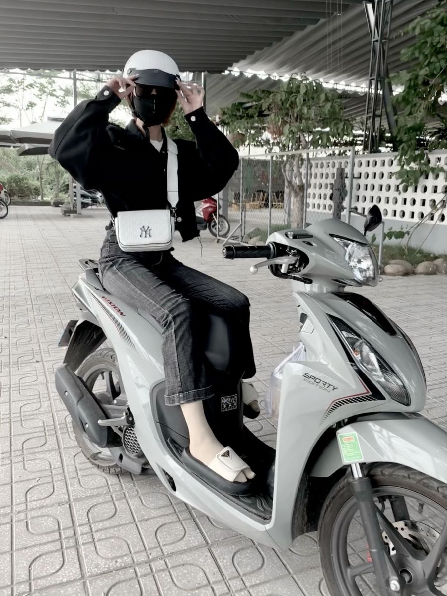 Gái xinh mặc áo khoác đen và quần jeans trên xe máy