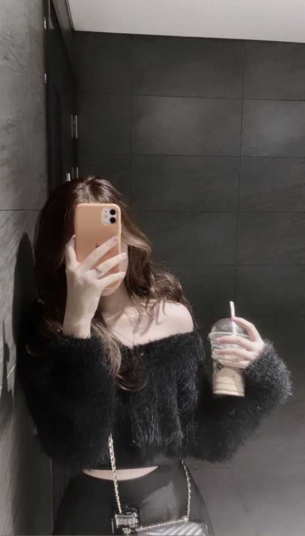 Gái xinh mặc áo len đen cam ly tự tin trong gương