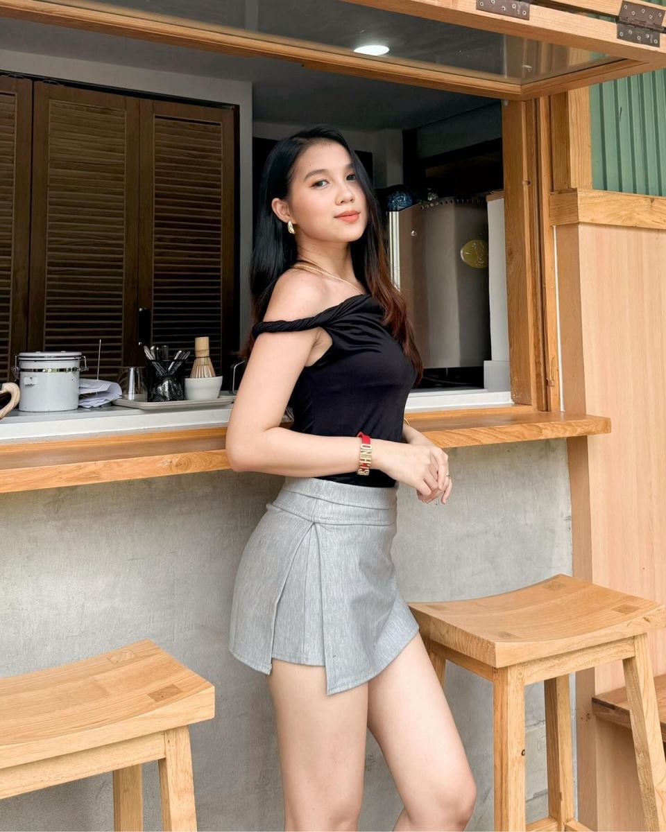 Gái xinh mặc áo phông đen và chân váy xếp ly màu xám